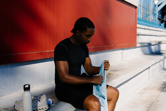 A well-built man on the bleachers dressing in athletic gear