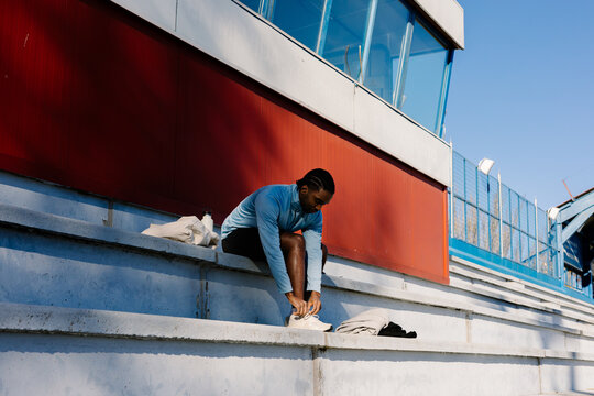 Runner seated in the stadium bleachers making sure his footwear si set