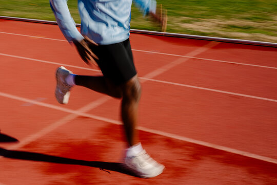 Motion-blurred view captures unknown sprinter racing along the track