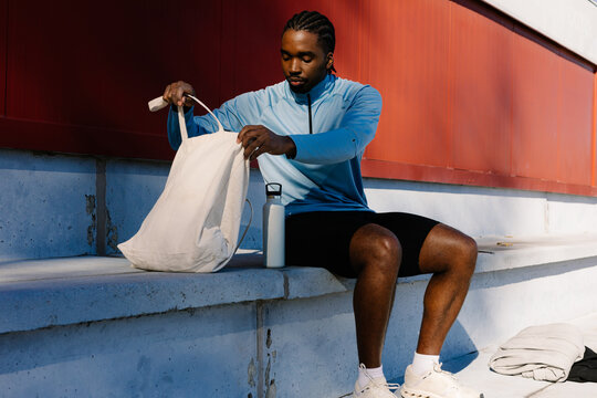 Full body shot of a young runner arranging his personal items