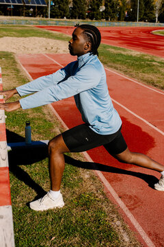 Trained runner carrying out dynamic leg stretches during his warm-up