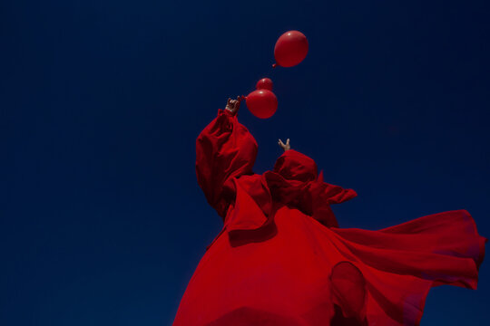 A girl in red with the red balloons 