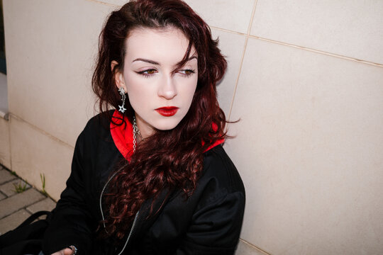 Thoughtful goth woman with red hair looking away