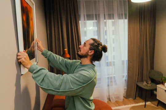 Man Hanging Picture Frame on Wall