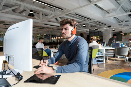 Man with headphones concentrating on graphic design work
