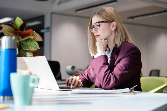 Businesswoman checking data on laptop at office desk
