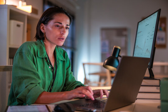 Woman working on laptop with financial data on screen.
