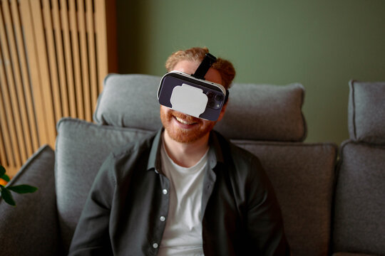 Man enjoys virtual reality while sitting on a couch at home
