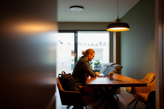 Person working at a table in a modern room with a warm light
