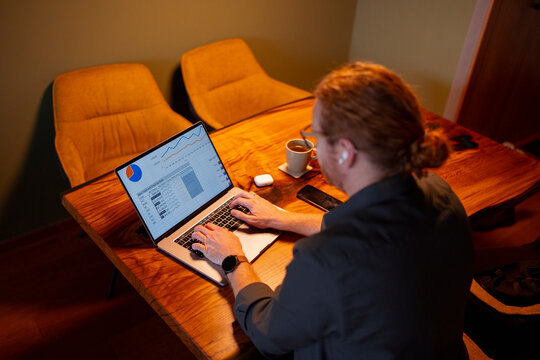 Working on a laptop at a wooden table with coffee in the evening

