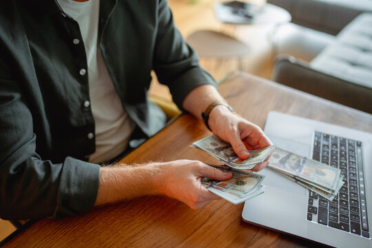 Counting money at a desk with a laptop on a sunny afternoon
