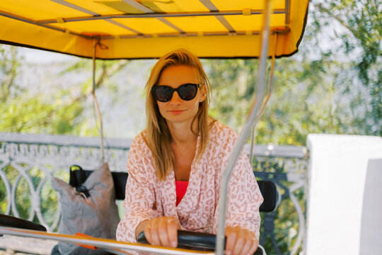 Woman Wearing Sunglasses Sits in a Yellow Rickshaw on a Sunny Day