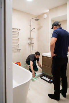 Men Working on Shower Installation With Laser Level And Meter