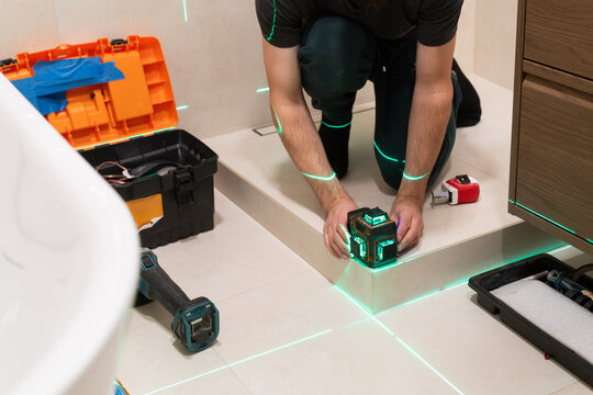 Worker Uses Laser Level to Align Glass Panels Of Shower