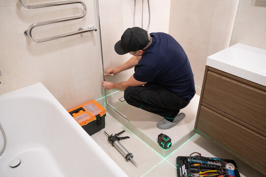 Worker Installs Shower Door Frame Using Tools 