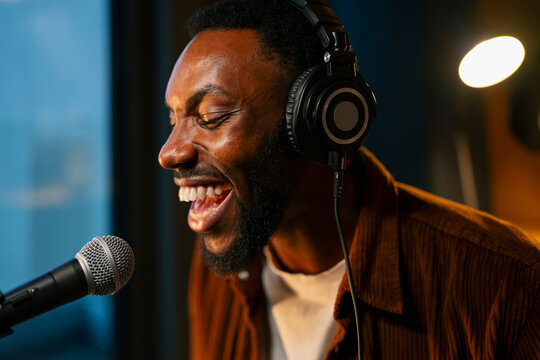 Man sings into mic with headphones
