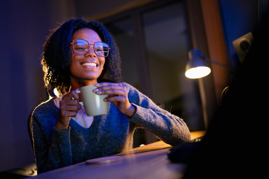 Smiling woman sips evening coffee
