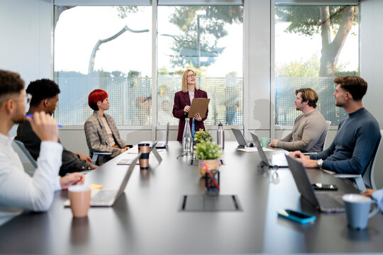 Businesswoman leading meeting with diverse team in modern office