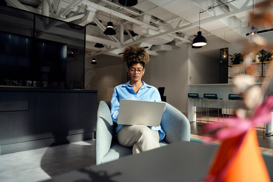 Woman working on laptop in modern office lounge