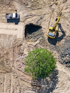 Aerial View Construction Site with Excavator, Truck and Leafy Tr