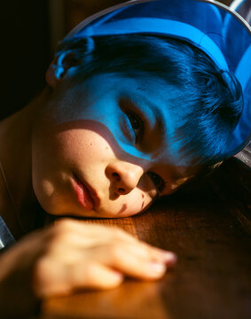 Child with blue light resting on wooden table