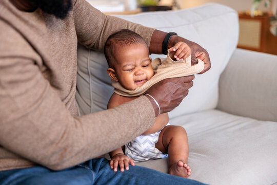 Father dressing unhappy baby.