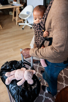 Father travels with baby in carrier and teddy bear.