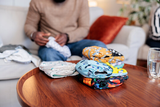 Man folding laundry with cloth diapers on a table.