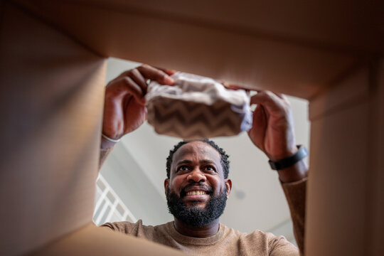Man smiles, pulling wrapped item from box.