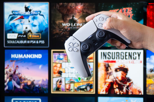 A hand holds a PlayStation 5 DualSense controller in front of a screen displaying games like GTA V -  Sonora, Mexico - February 6, 2026