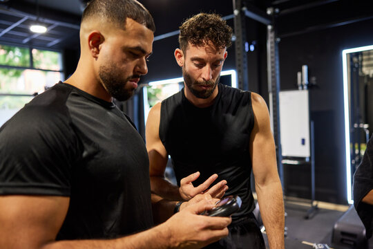 Two men discuss workout routine in gym setting