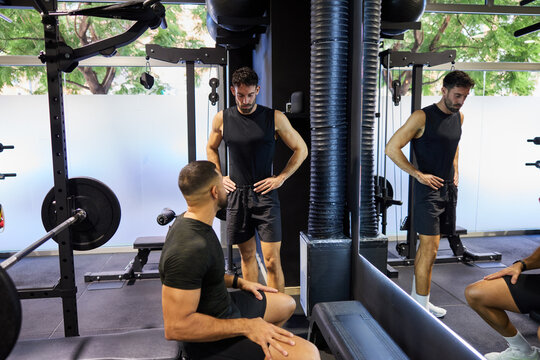 Man talks to friend during workout session in gym