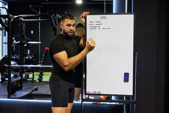 Trainer writing a workout plan on a whiteboard at the gym