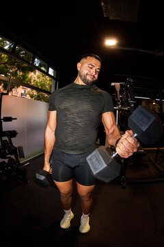 Man lifts dumbbell in gym during workout session for strength tr