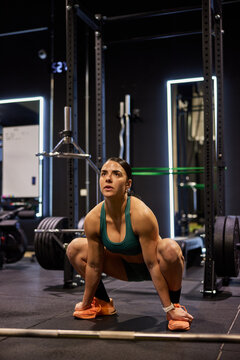 Woman lifts weights in gym during evening workout session