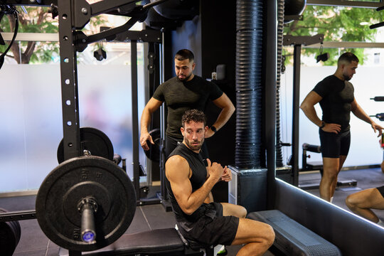 Two men workout in gym with weights and training equipment
