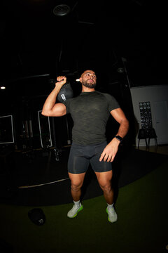 Man lifting weights in gym during evening workout session
