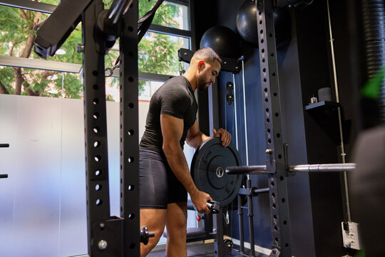 Man lifts weight in gym during daytime workout session