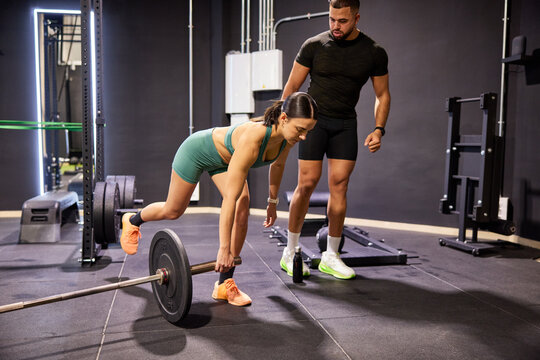 Training session with weights in gym with instructor and athlete