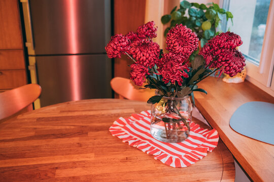 Flowers in a vase on a wooden table in the kitchen