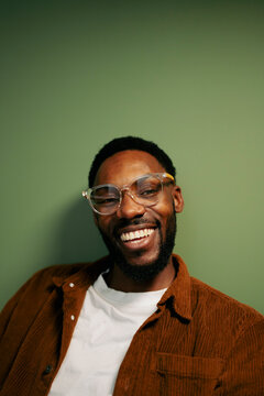 Man smiling in front of green wall

