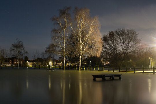 A park table surrounded by flood water, on a winters night