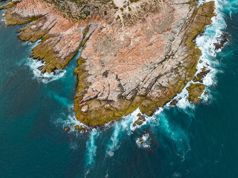 Waves crashing on a rocky coastline covered on colorful lichen