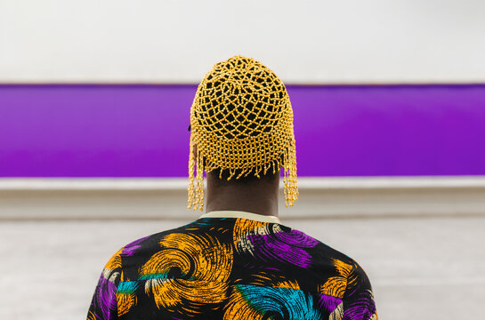 Portrait of man in beaded headpiece facing wall