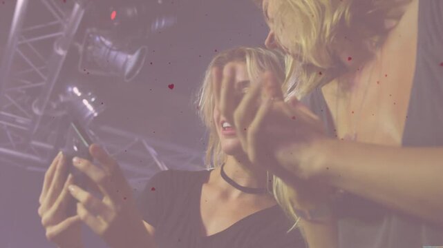 Two women leaning viewing phone tapping screen causing animated confetti celebrating live event