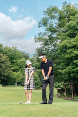 ゴルフ場でゴルフを教えるゴルファーの男性と女性