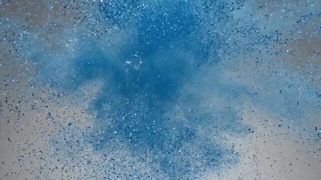 Abstract blue particles explode with iridescent bubbles against a soft gray background