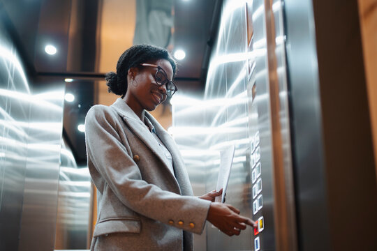 Woman in elevator pressing button
