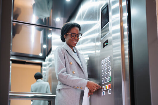 Woman in elevator pressing buttons
