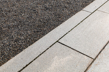 Stone curb beside gravel and pavement